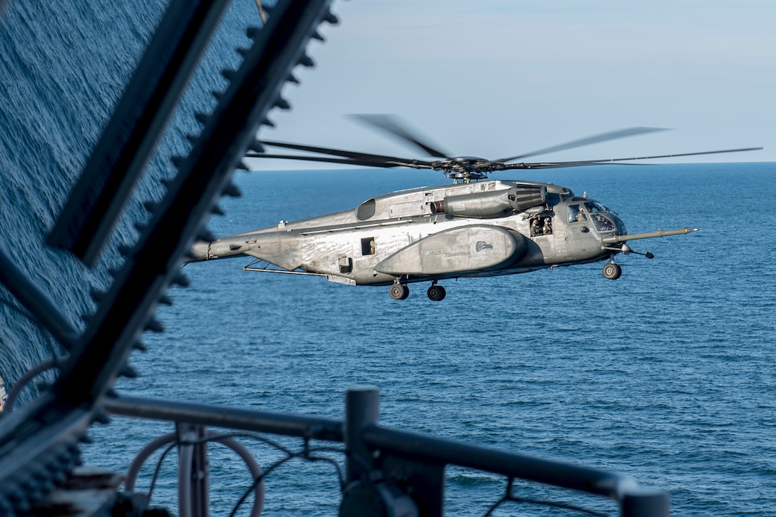 A helicopter prepares to land aboard an aircraft carrier.