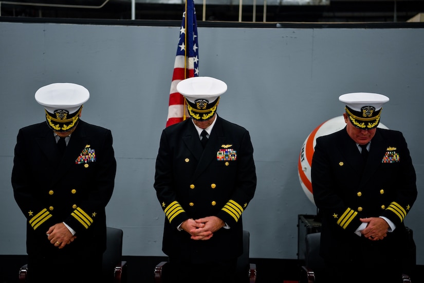 From left, Cmdr. William Edenbeck, Navy Munitions Command Atlantic Unit Charleston commanding officer, Capt. Jake Jacobs, Navy Munitions Command Atlantic commander, and Cmdr. Patrick Sutton, former NMC commanding officer, bow their heads during the closing benediction of their change of command ceremony Jan. 16, 2018.
