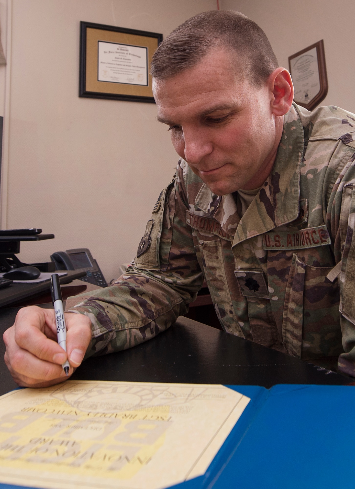 Lt. Col. David Thompson, 379th Expeditionary Aircraft Maintenance Squadron commander, reviews an innovation award citation Jan. 17, 2019, at Al Udeid Air Base, Qatar. Thompson implemented the award program to recognize Airmen in his squadron who improve programs and processes within his unit. Tech. Sgt. Bradley Newcomb, 379th EAMXS was presented the award in December, 2018, for coming up with a better standard procedure to set up and tear down RC-135 Rivet Joint air carts, saving a total of 480 man hours a month. (U.S. Air Force photo by Tech. Sgt. Christopher Hubenthal)