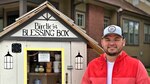 Man stands in front of charitable food and supply collection box.