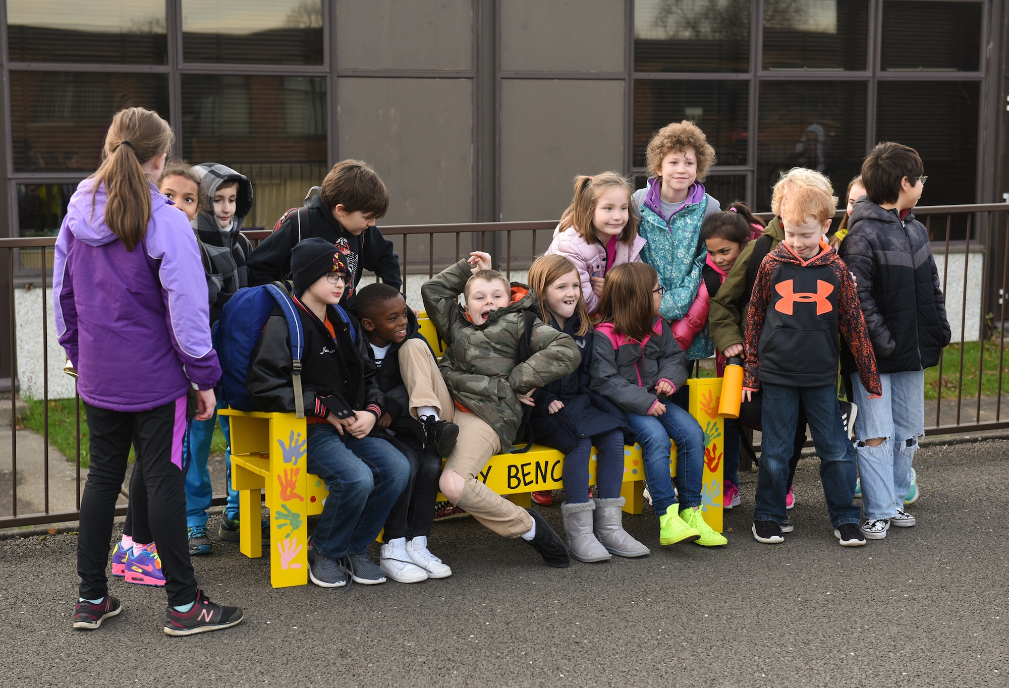 Children at the RAF Alconbury Elementary School sit on the new Buddy Bench at RAF Alconbury, United Kingdom, Jan.15, 2019. The new Buddy Bench has been placed at the base elementary school to promote kindness and healthy relationships within the school system. (U.S. Air Force photo by Airman 1st Class Jennifer Zima)