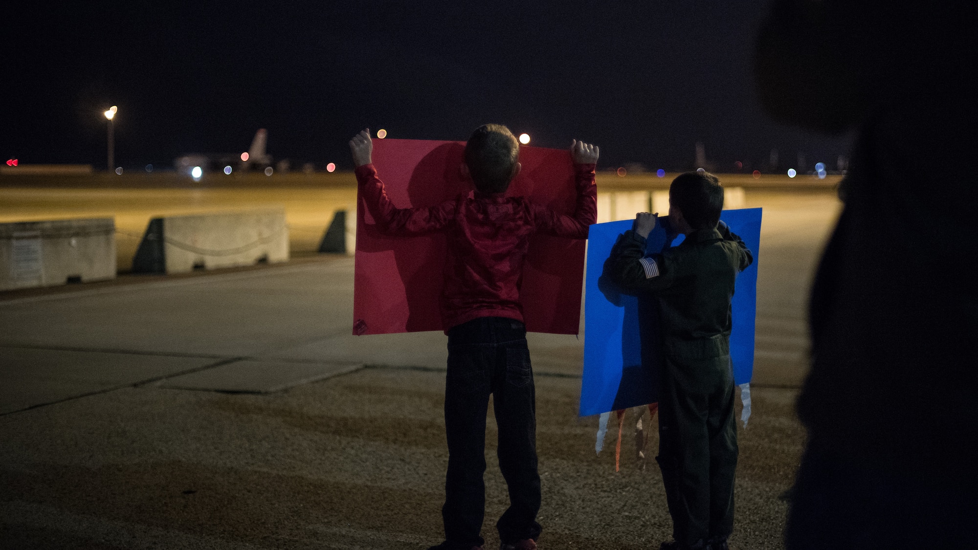Two boys raise posters for their father returning from a deployment at Barksdale Air Force Base, La., Jan. 16, 2019. Their father is part of the 96th Bomb Squadron that deployed to Andersen Air Force Base, Guam. (U.S. Air Force photo by Airman 1st Class Lillian Miller)