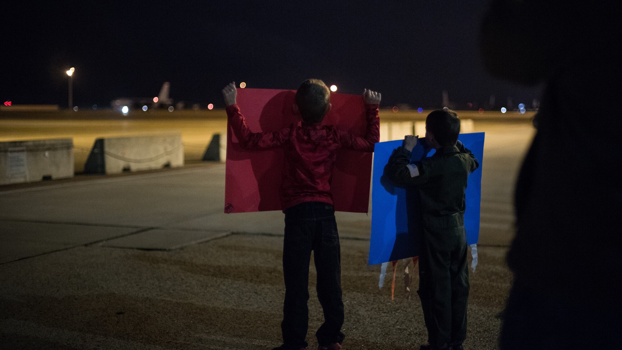 Two boys raise posters for their father returning from a deployment at Barksdale Air Force Base, La., Jan. 16, 2019. Their father is part of the 96th Bomb Squadron that deployed to Andersen Air Force Base, Guam. (U.S. Air Force photo by Airman 1st Class Lillian Miller)