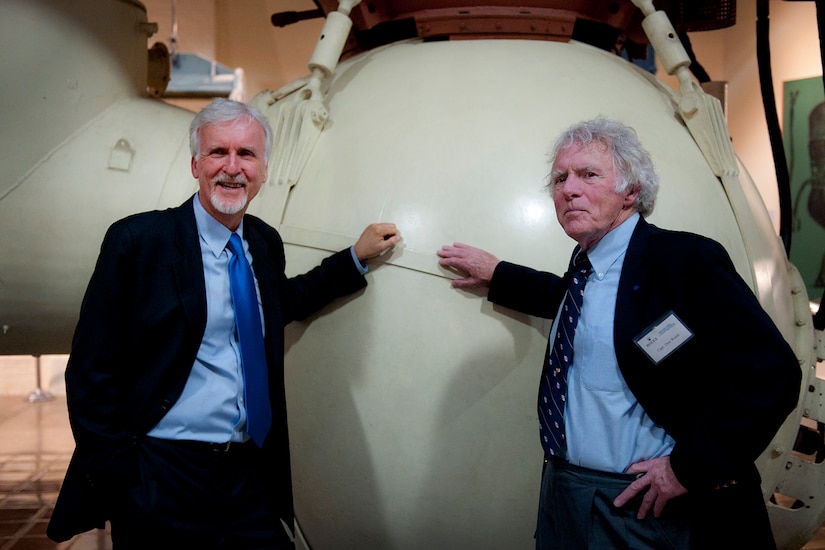 Two men stand near a submersible on display.