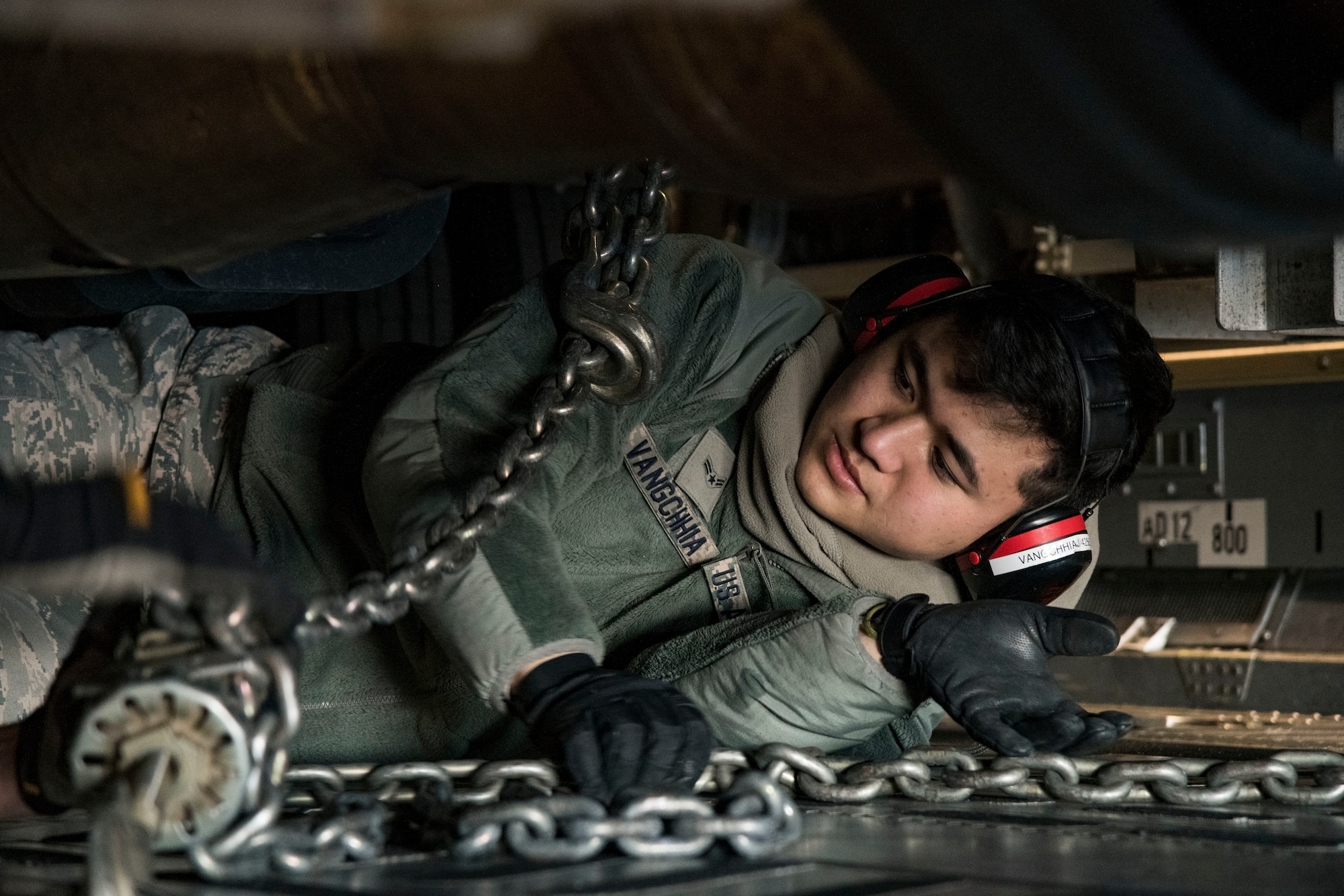 Underneath a vehicle, Airman 1st Class Jacob Vangchhia, 436th Aerial Port Squadron ramp operations specialist, attaches cargo chains to secure a vehicle to a C-17 Globemaster III cargo floor Jan. 11, 2019, at Dover Air Force Base, Del. Vangchhia and other ramp operations personnel loaded five vehicles belonging to the Delaware National Guard's 31st Civil Support Team, Weapons of Mass Destruction headquartered in Smyrna, Del. (U.S. Air Force photo by Roland Balik)