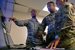 Senior Airman David Daniel, left, with the Maryland Air National Guard's 275th Cyber Operations Squadron, points out key pieces of information on cyber defense operations to Army Maj. Steven Jackson, assistant intelligence officer with with the Mississippi National Guard, and Army Staff Sgt. Nyesha Bradley, with the Louisiana Army National Guard's D Company, 769th Brigade Engineer Battalion, during exercise Cyber Shield 17 at Camp W.G. Williams in Bluffdale, Utah, in April 2017.