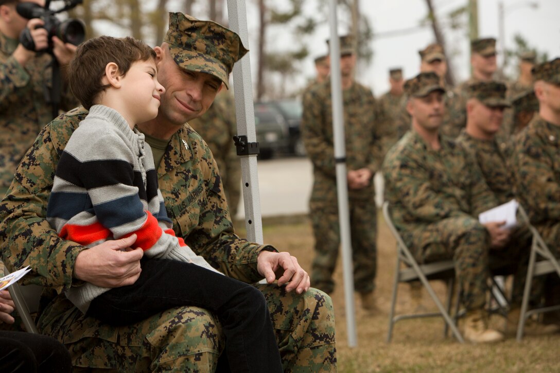 A young boy sits on the lap of his father.