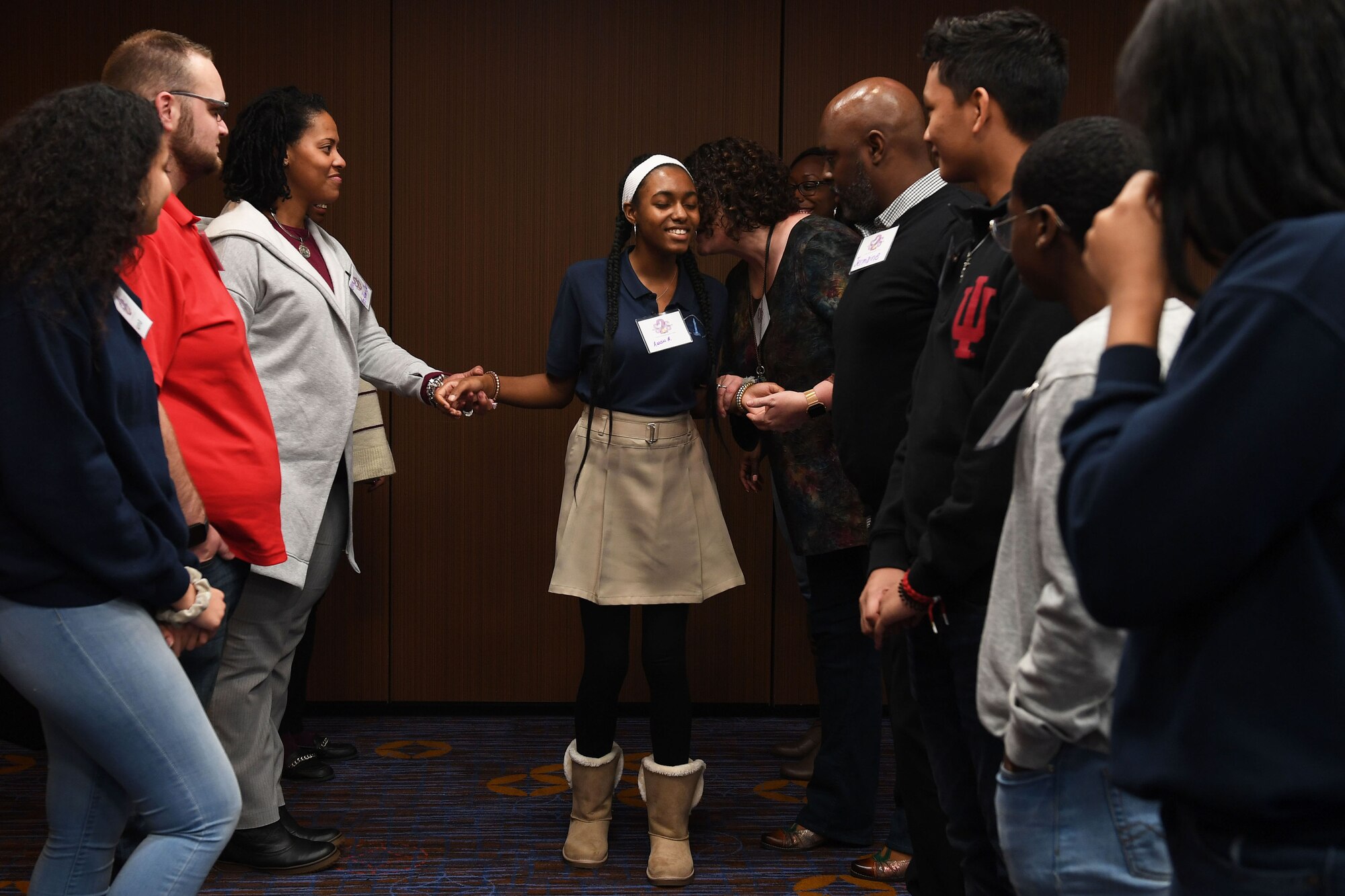 Six people stand up in the front of a room speaking.