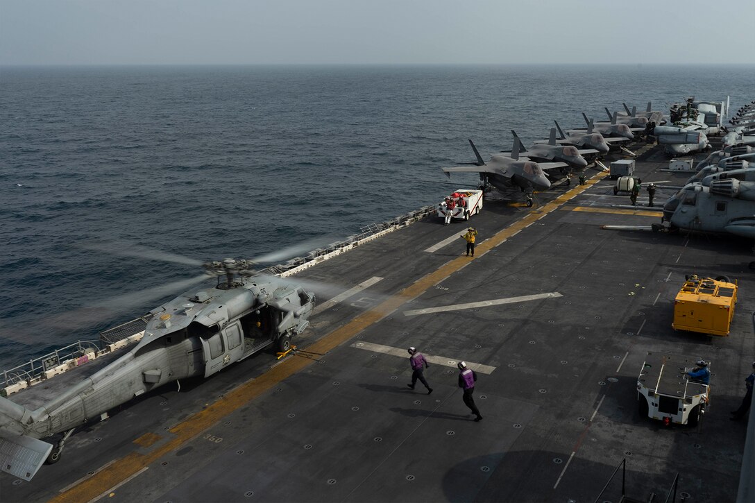 Sailors run to refuel an MH-60S Seahawk helicopter.