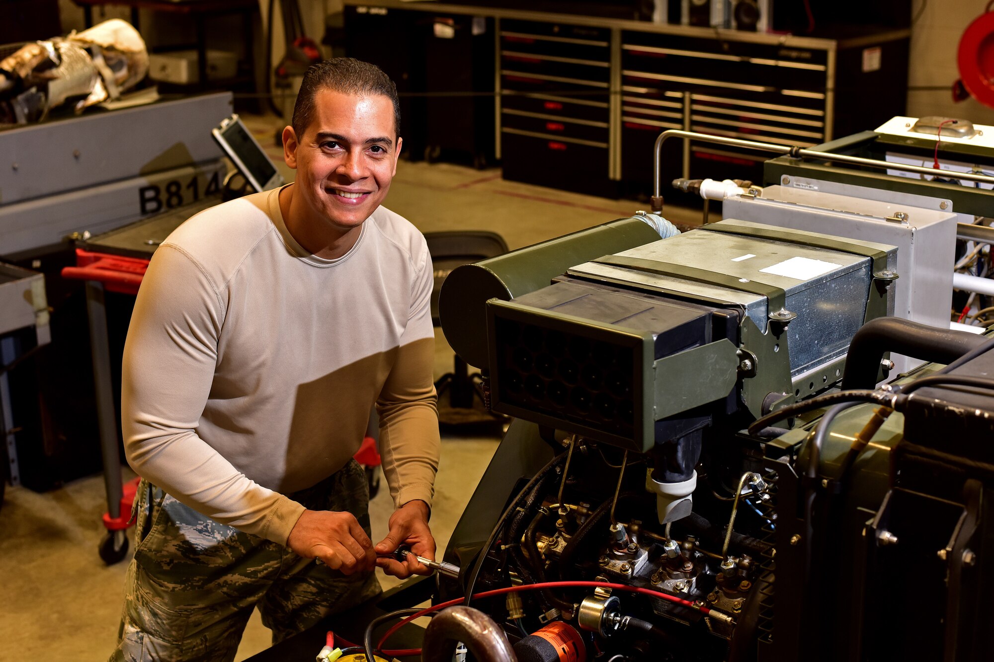 Man holding socket wrench working on equipment smiling at camera