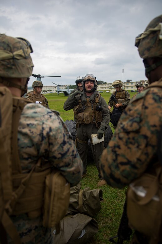 An MV-22B Osprey crew chief gives a safety brief to landing support specialists during helicopter support team training at Camp Foster, Okinawa, Japan, Jan. 14, 2019. Landing Support Company, 3rd Transportation Support Battalion, Combat Logistics Regiment 3, 3rd Marine Logistics Group supported Marine Medium Tiltrotor Squadron 265, Marine Aircraft Group 36, 1st Marine Aircraft Wing during external lift training, which ensures pilots and landing support specialists are able to communicate as well as transport gear from one location to another. (U.S. Marine Corps Photo by Cpl. André T. Peterson Jr.)