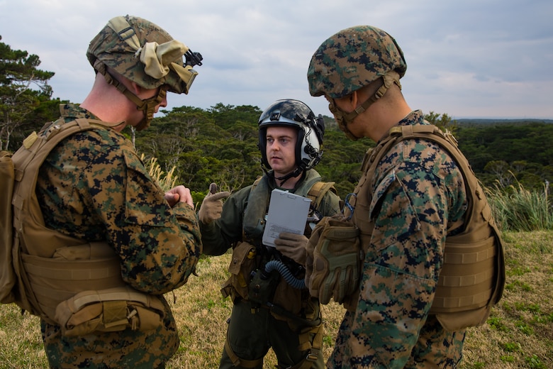 An MV-22B Osprey pilot speaks to landing support specialists during helicopter support team training at Camp Hansen, Okinawa, Japan, Jan. 14, 2019. Landing Support Company, 3rd Transportation Support Battalion, Combat Logistics Regiment 3, 3rd Marine Logistics Group supported Marine Medium Tiltrotor Squadron 265, Marine Aircraft Group 36, 1st Marine Aircraft Wing during external lift training, which provides valuable flight training hours for pilots as well as field training for LS Co. Marines. (U.S. Marine Corps Photo by Cpl. André T. Peterson Jr.)