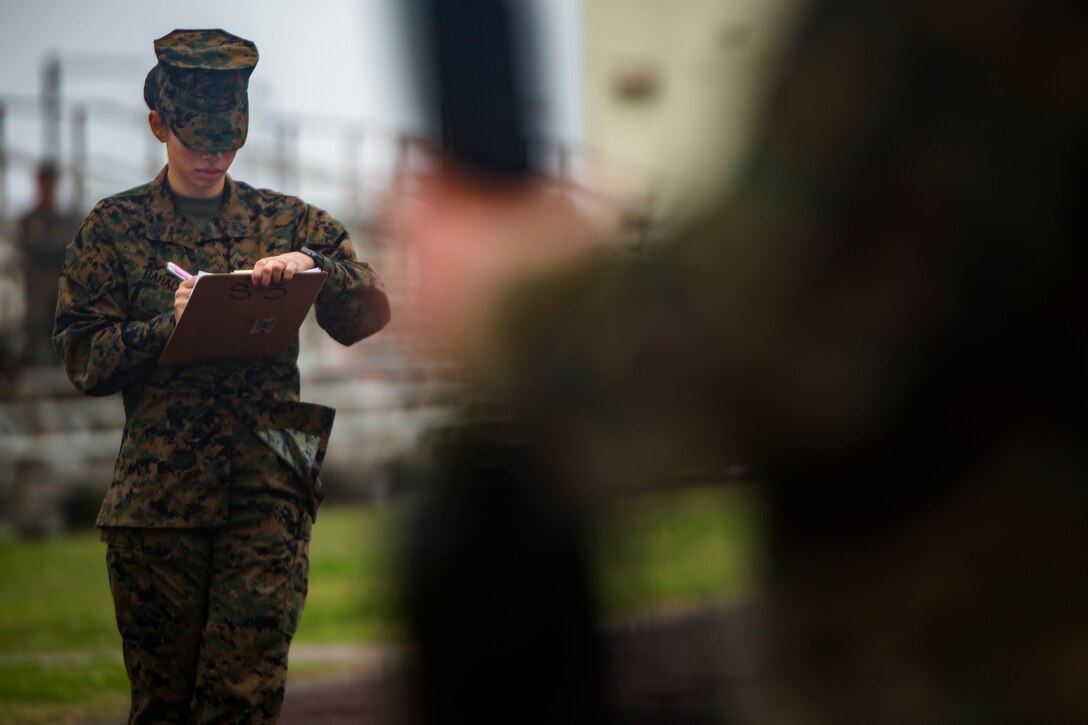 Staff Sgt. Jennifer Barack grades a platoon of Marines as they conduct close order drill during a drill competition at Roberts Field, Camp Kinser, Okinawa, Japan Jan. 16, 2019. Close order drill is conducted by the Marine Corps to teach simple formations, discipline and small unit leadership. This is the first drill competition Supply Battalion, Combat Logistics Regiment 35 has hosted and it will now be held quarterly. Barack, a supply administrator with Headquarters and Support Company, Supply Bn., is a native of Apollo Beach, Florida.  (U.S. Marine Corps photo by Lance Cpl. Jamin M. Powell)