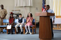 Braylen Hills, a young boy from the Camp Kinser School Age Care Program, recited part of Dr. Martin Luther King Jr.’s “I Have a Dream” speech during a commemorative service at Camp Kinser, Okinawa, Japan, Jan. 18, 2019. Hills was one of four youth representatives who spoke at the event alongside Natalie Brown, center, Domonic Zagone, center left, and Makayla Brantley, far left. (U.S. Marine Corps photo by Cpl. Isabella Ortega)