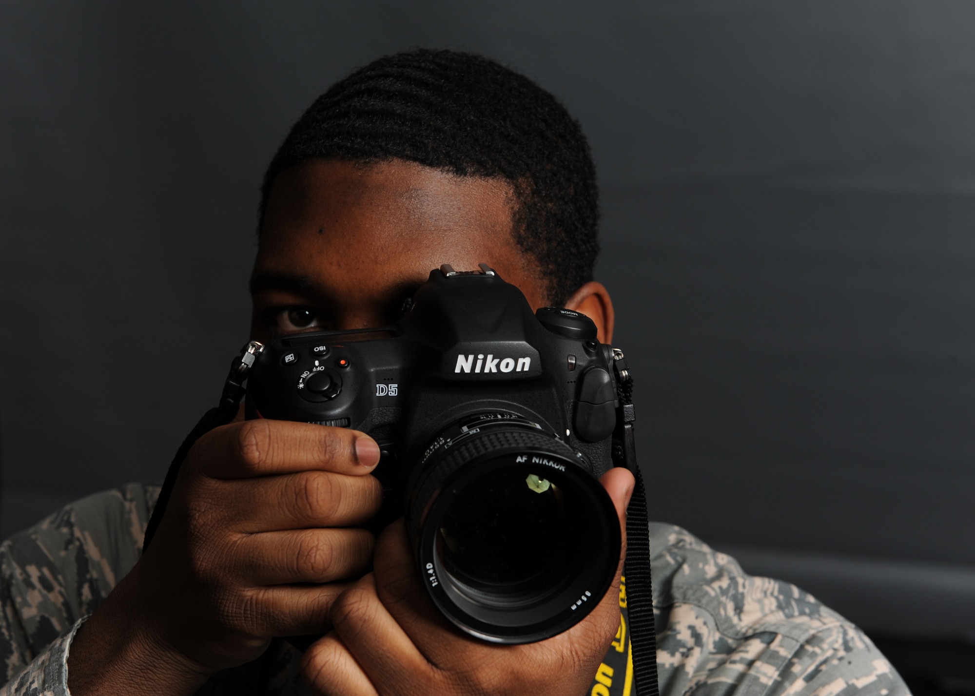 Airman 1st Class Octavius Thompson poses for a photo with a camera in his hand.