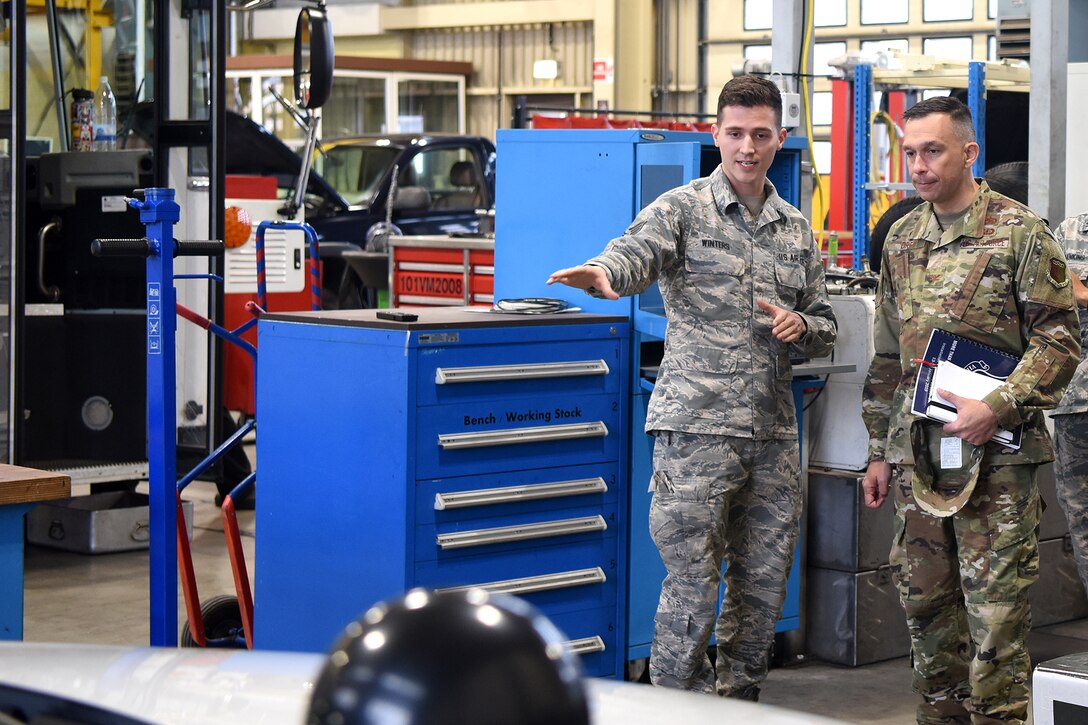 U.S. Air Force Staff Sgt. Zachari Winters, 86th Vehicle Readiness Squadron vehicle maintenance and customer service representative, shows U.S. Air Force Col. Lyle Drew, 78th Air Base Wing commander, a new innovation in their auto shop. Winters explained how the 86th VRS streamlined their vehicle repair process.