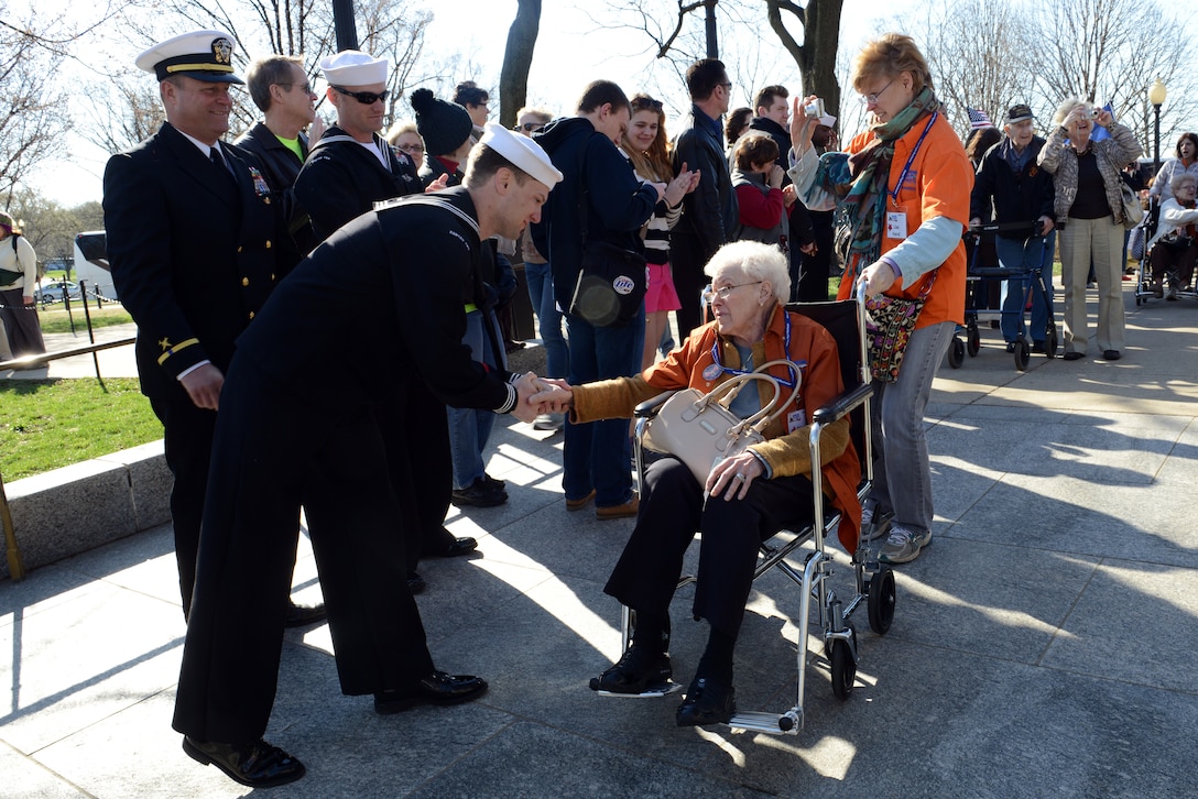 A group of people greet a woman in a wheelchair.