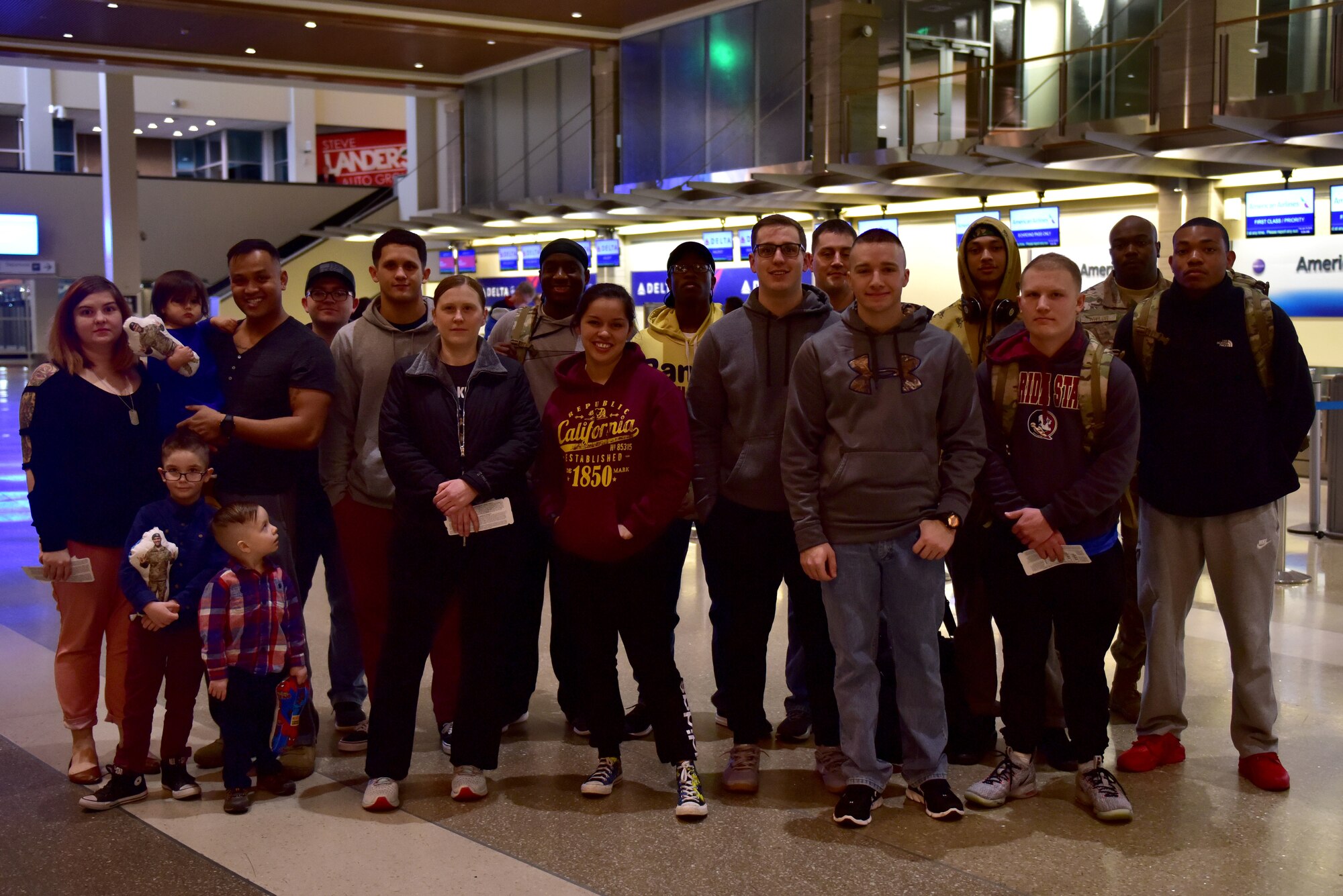 A group of people stand and smile at the camera in an Airport.