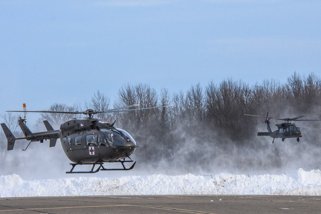 Helicopters take off in the snow.