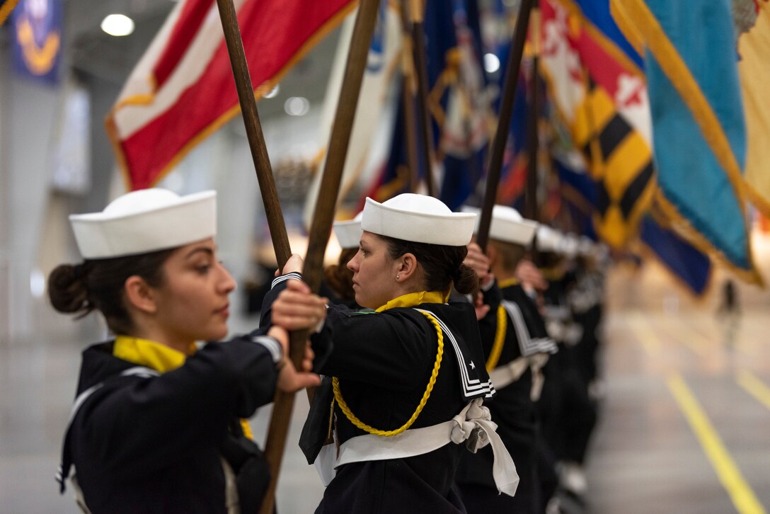 A group of Sailors holding flags in a line.