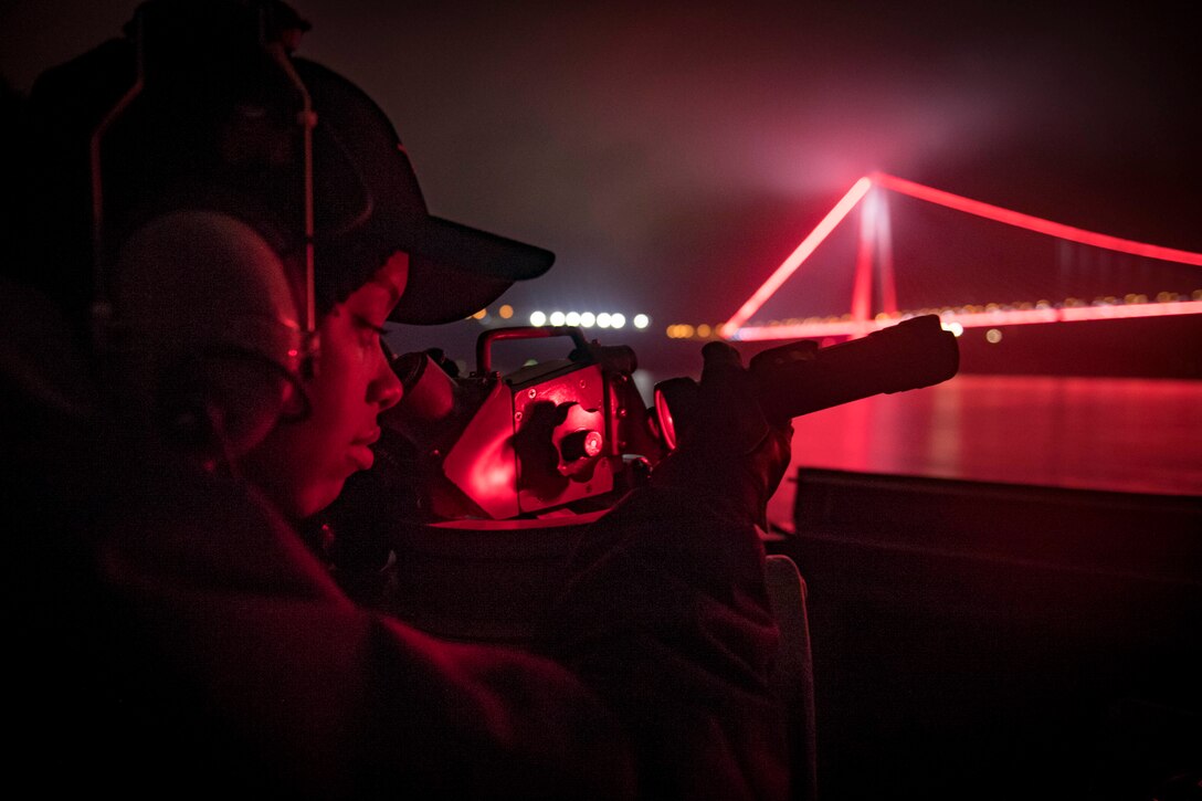 A service member stands watch on a ship.