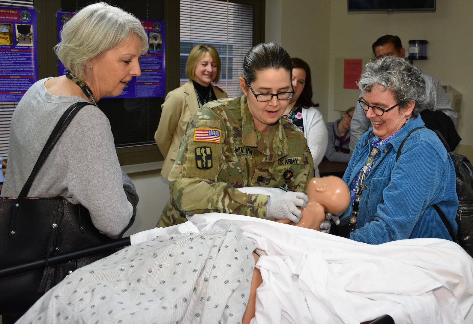 University of Vermont's medical school advisor Cara Calvelli (left) and Marguerite Degenhardt (right) of North Central College witness the birth of "Baby Simi" in the training delivery room of Brooke Army Medical Center at Joint Base San Antonio-Fort Sam Houston. Advisors from several institutions attended the Medical Advisor Army Experience Tour,from North Central College, Beaumont Health System, Western Michigan University Homer Stryker M.D. School of Medicine, Farmingdale University, West Virginia Health System, University of Vermont and Dartmouth University.