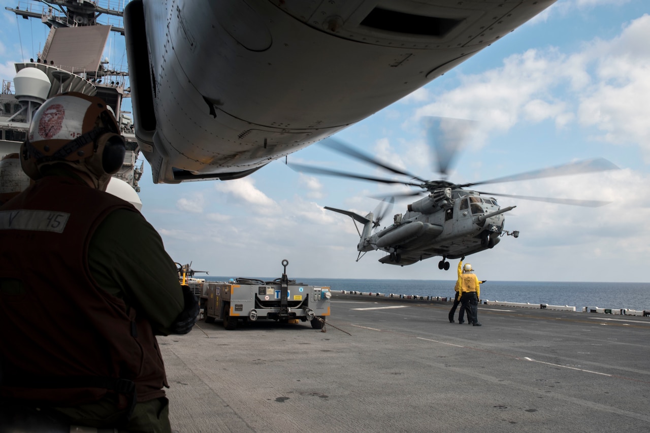 A helicopter hovers over a ship.