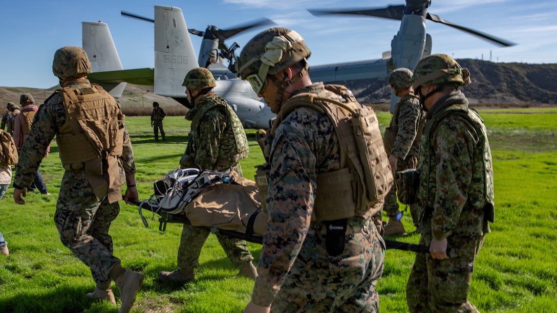 U.S. Marines and Sailors assigned to 1st Marine Logistics Group and Japan Ground Self-Defense Force Soldiers with 1st Amphibious Rapid Development Regiment, Move simulated casualties to a MV-22B Osprey tiltrotor aircraft for medical evacuation training during Iron Fist,