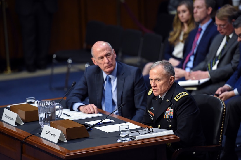 A soldier and a civilian sit at a table.