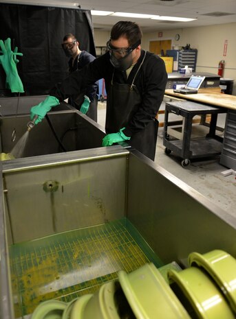 Airman 1st Class Colby Brown (left) and Senior Airman Uriah Cleek, 9th Maintenance Squadron non-destructive inspection (NDI) technicians, perform a fluorescent inspection process on aircraft parts.
