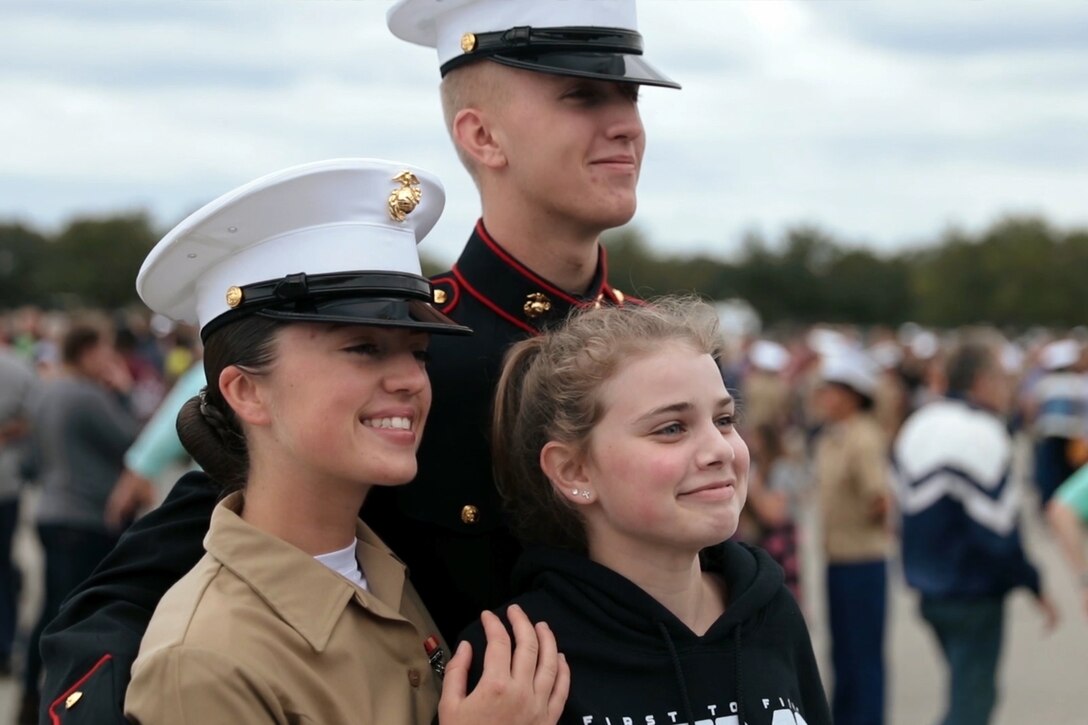 Two Marines take a photo with their sister.