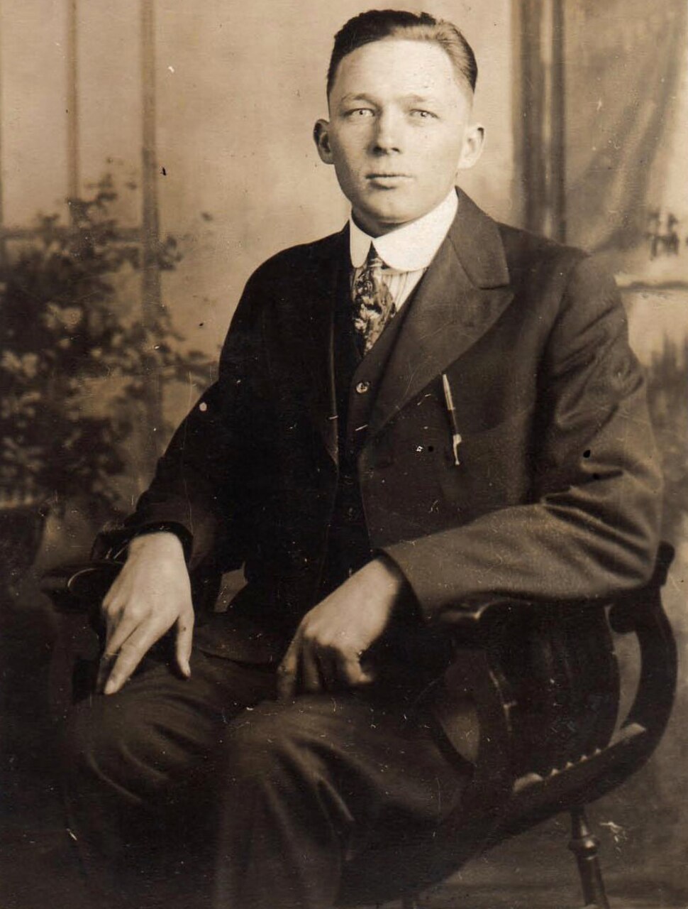 A man dressed in a suit sits in a chair.