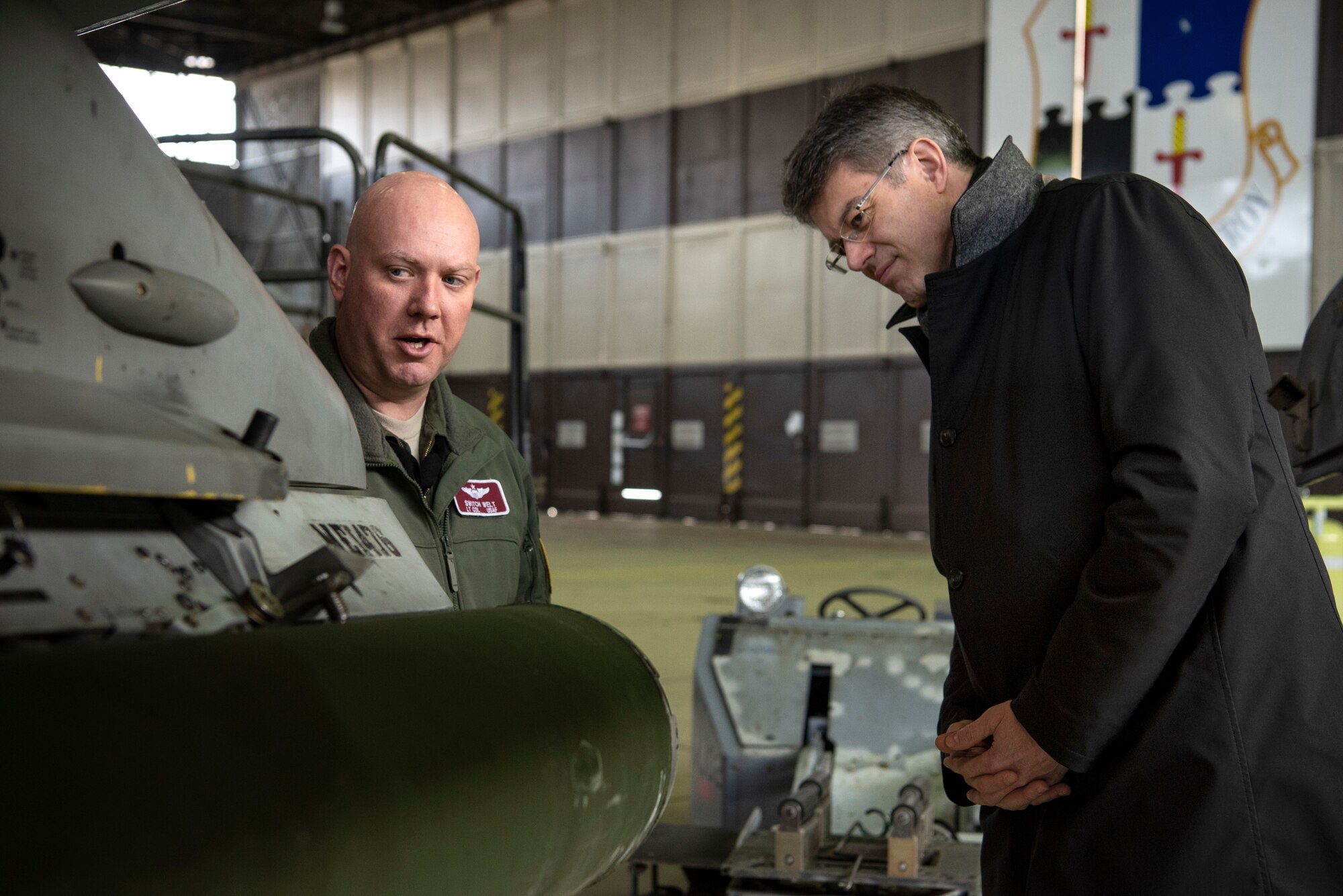 U.S. Air Force Lt. Col. David Welt, 52nd Operations Support Squadron director of operations, left, speaks with Patrick Schnieder, member of the German Federal Parliament in Berlin, right, in Hangar 1 at Spangdahlem Air Base, Germany, Jan. 24, 2019. Members of the 52nd Fighter Wing gave Schnieder a base tour to provide him a better understanding of the wing's aircraft and operations. (U.S. Air Force photo by Airman 1st Class Valerie Seelye)