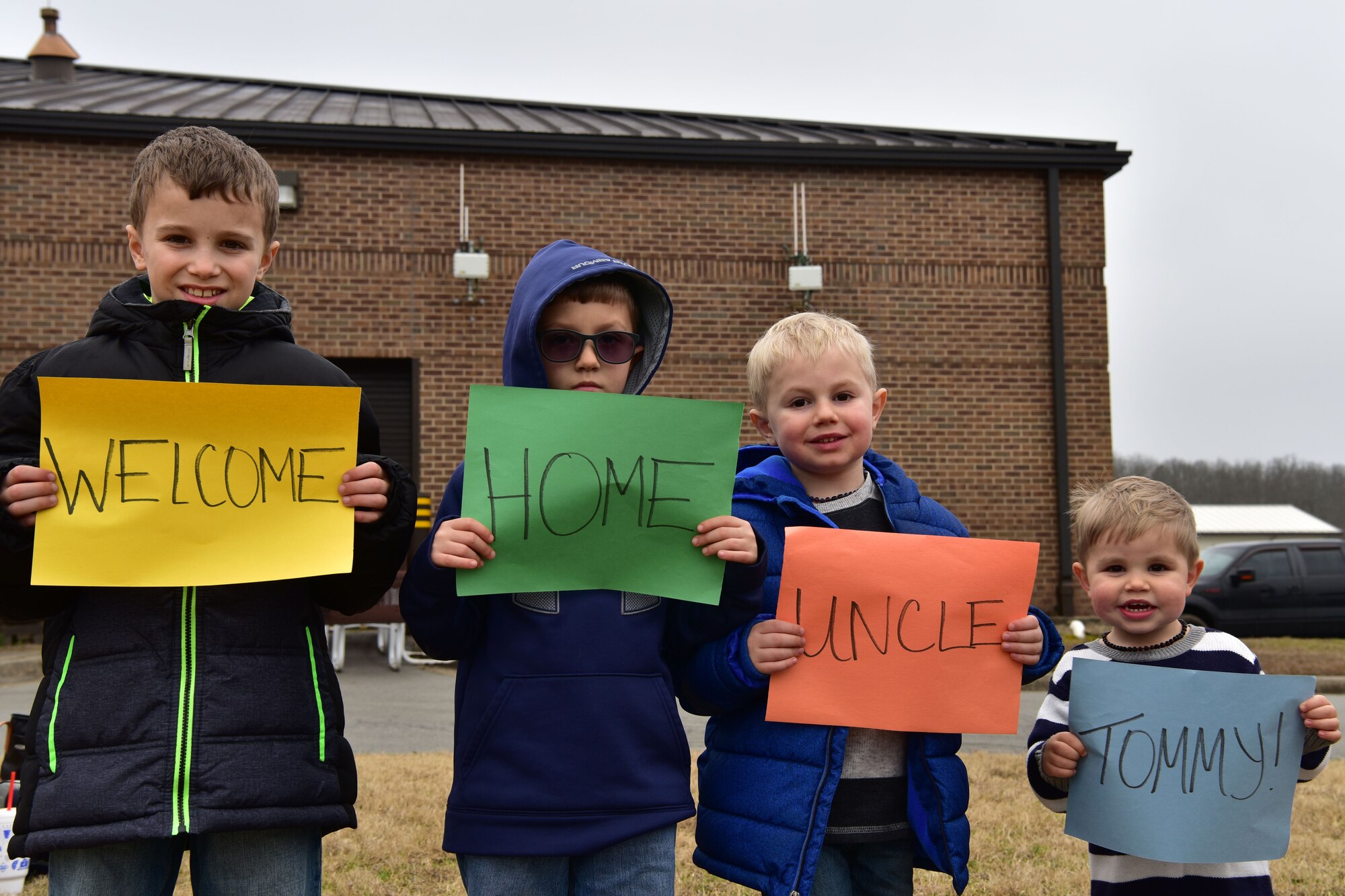 Four young children hold up signs for Airmen returning from deployment.