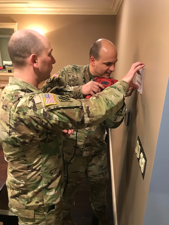 Two male Soldiers drilling into wall