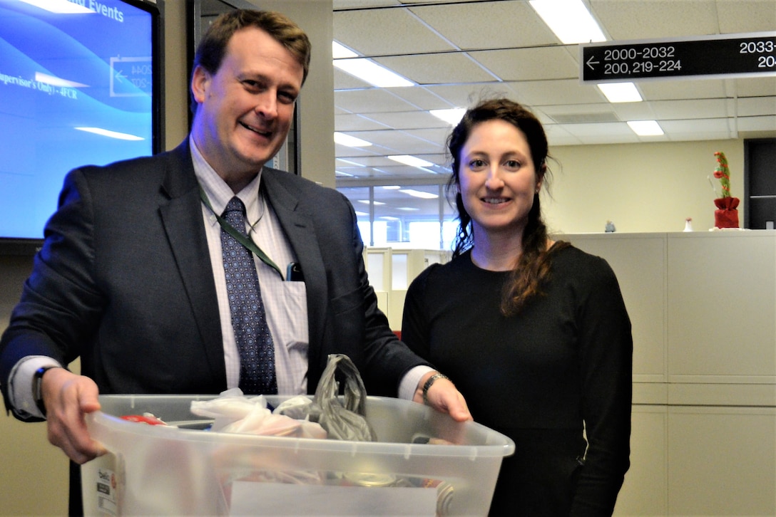 a man and woman hold a container of nonperishable food