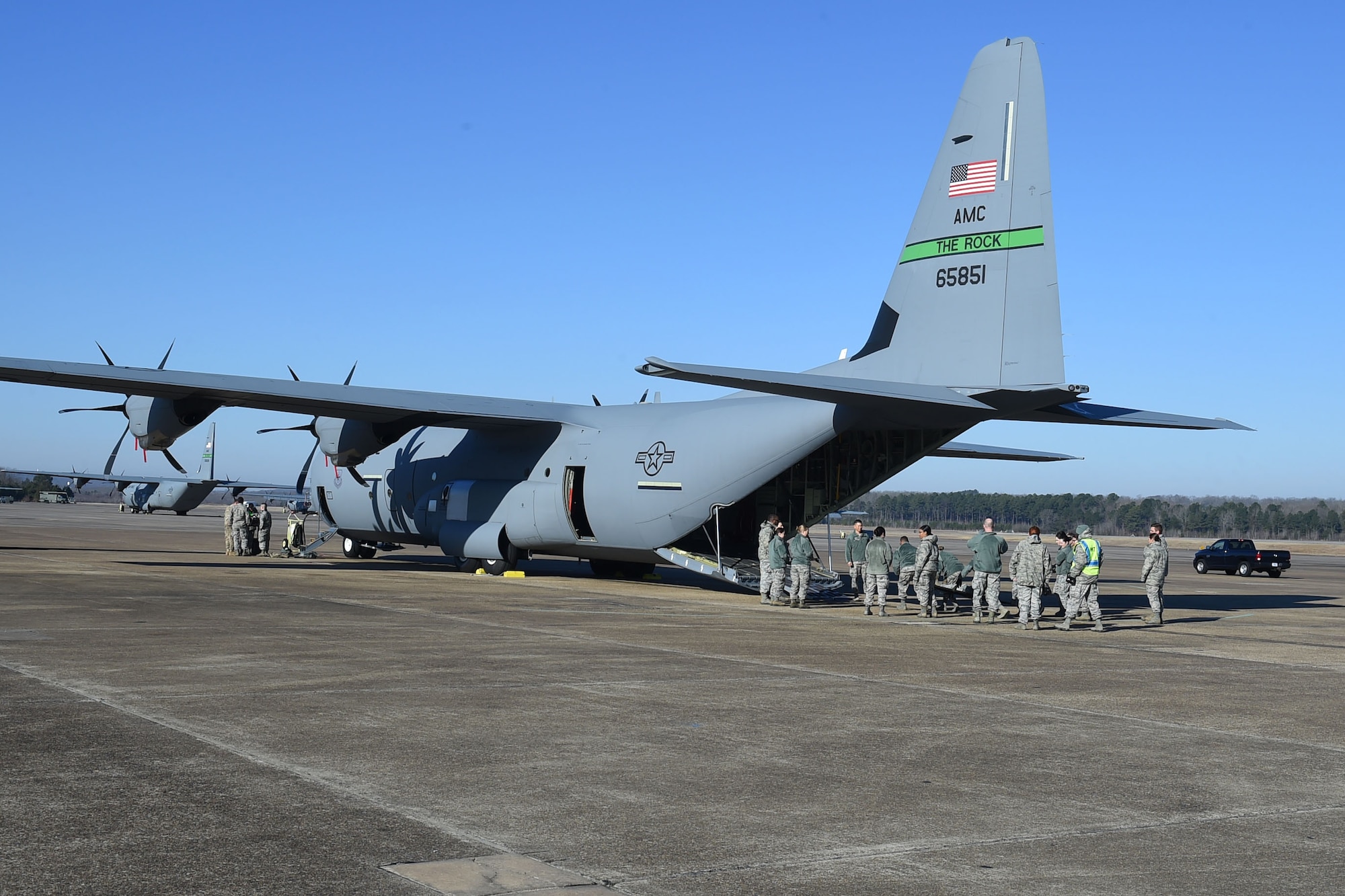 Airmen lift an Airman on a litter inside a C-130J,