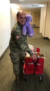 Male Soldier holding toys donated to Ronald McDonald House