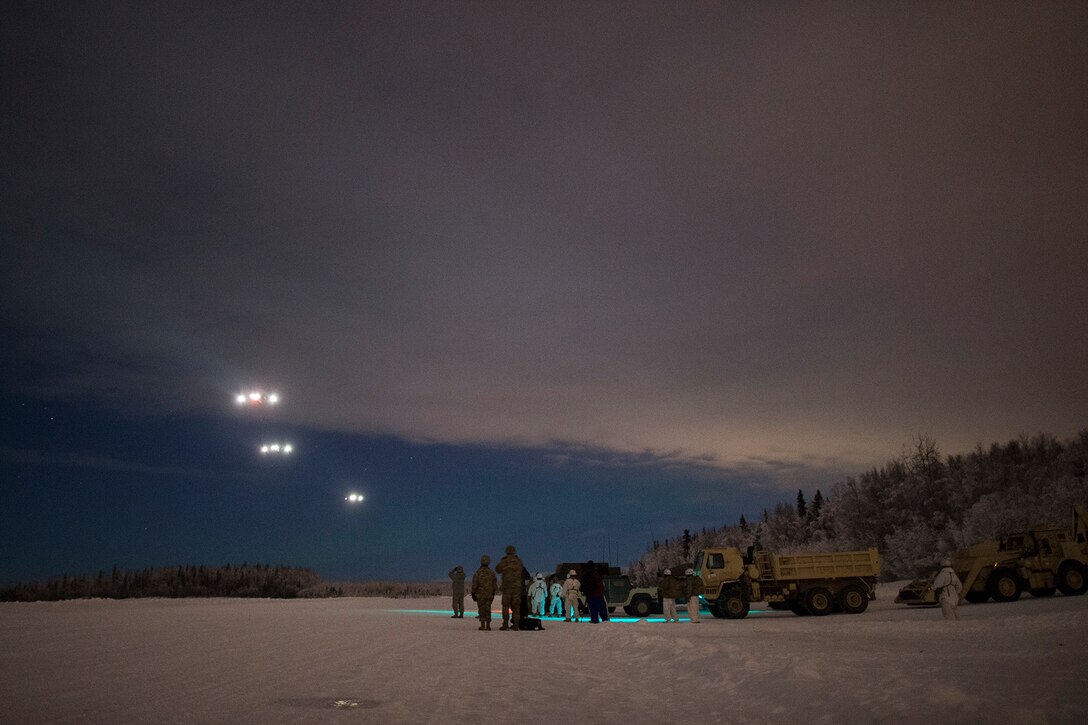 Soldiers watch the approach of three Air Force C-17 Globemaster aircraft.