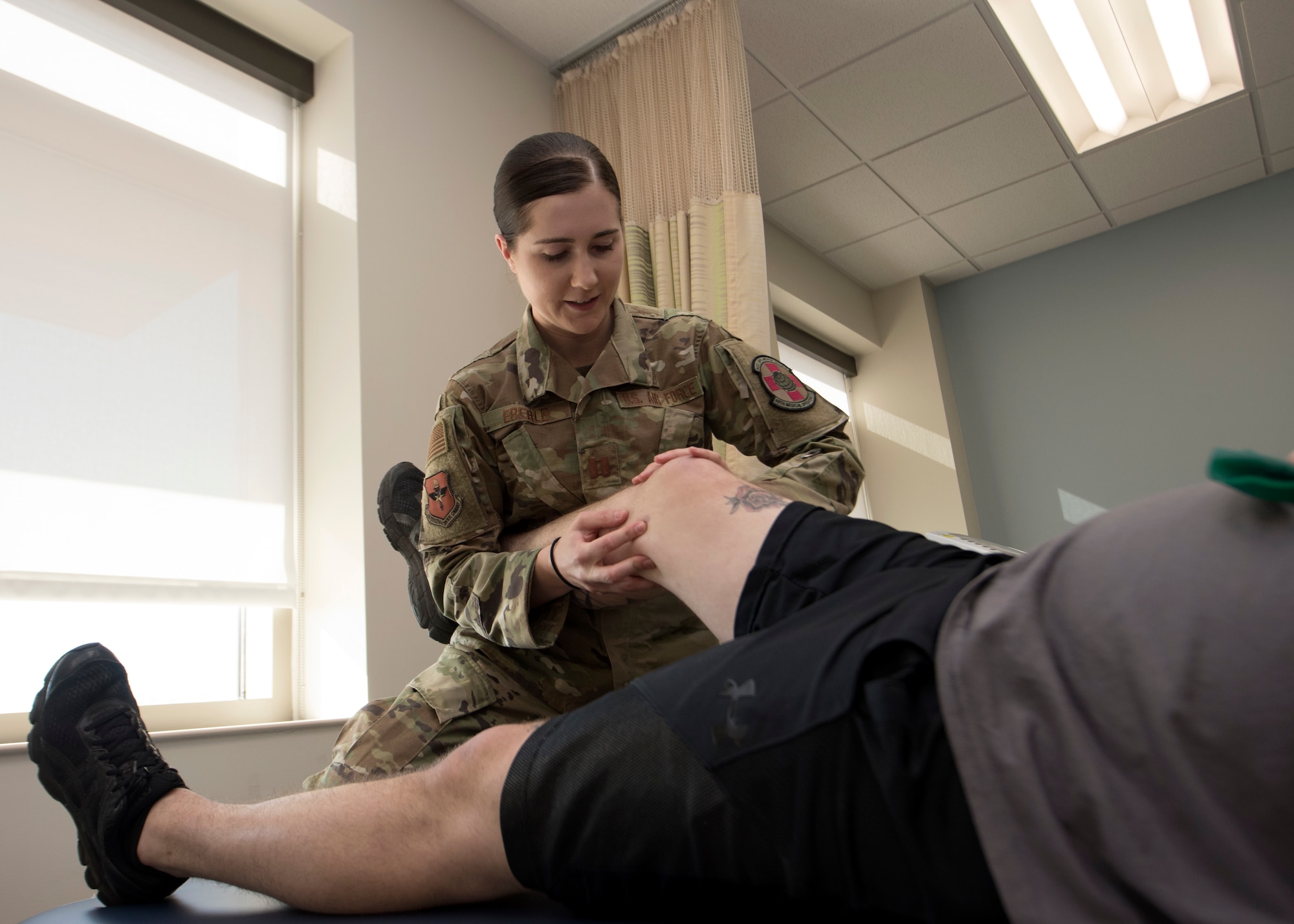 An Air Force officer holds a man's leg.