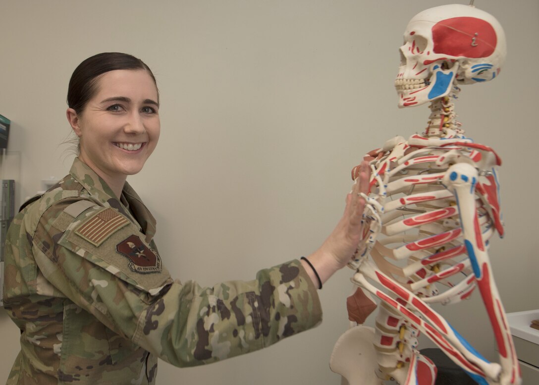 An Air Force officer poses with a plastic skeleton.