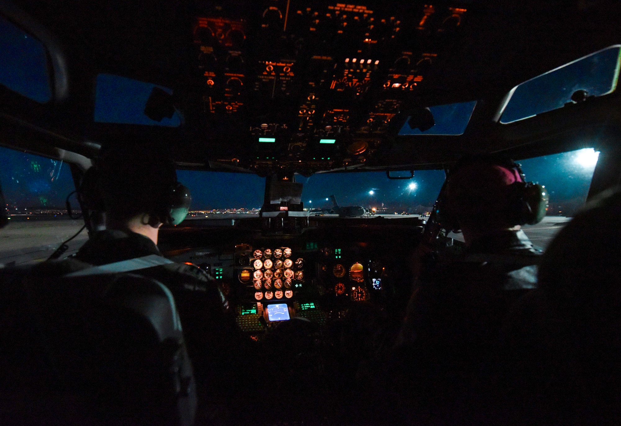 Pilots sit in a cockpit and prepare for take off.