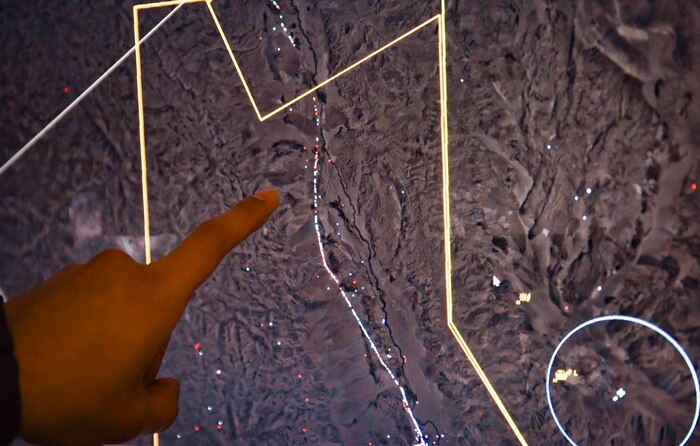 An Airman points to a dot on a radar screen.