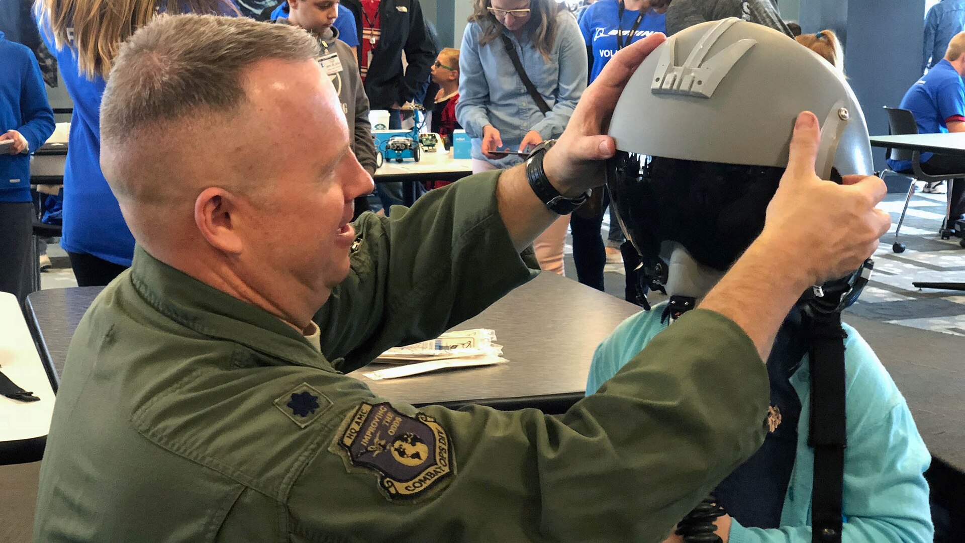 Man puts flight helmet on child.