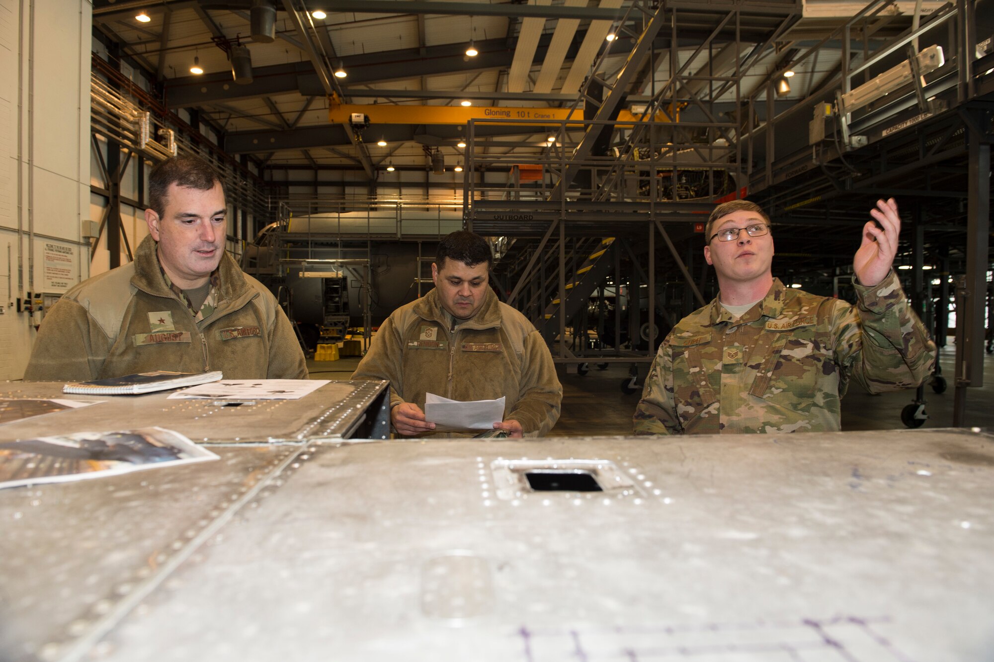 U.S. Air Force Staff Sgt. Justin Cupit, 86th Maintenance Group facility manager (right), discusses plans to install a fall prevention system with U.S. Air Force Brig. Gen. Mark R. August, 86th Airlift Wing commander (left), and U.S. Air Force Chief Master Sgt. Ernesto Rendon, 86th AW command chief (middle), in the dual bay hanger on Ramstein Air Base, Germany, Jan. 24, 2019. August awarded Cupit as the Airlifter of the Week for his efforts in maintaining more than 40 86th MXG buildings worth more than $60 million. (U.S. Air Force photo by Staff. Sgt. Jonathan Bass)