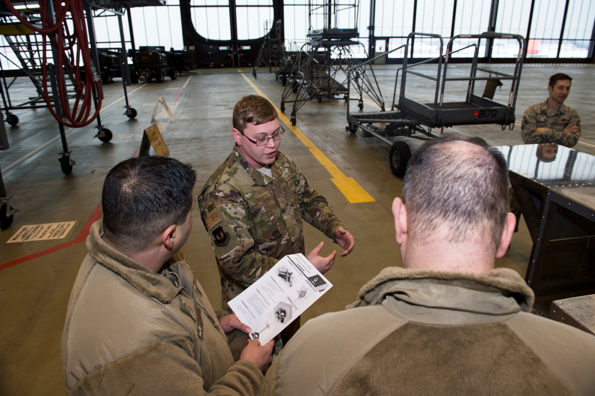 U.S. Air Force Staff Sgt. Justin Cupit, 86th Maintenance Group facility manager (middle), discusses details regarding a construction project with the 86th Airlift Wing command team in the dual bay hanger on Ramstein Air Base, Germany, Jan. 24, 2019. August awarded Cupit as the Airlifter of the Week for his efforts in maintaining more than 40 86th MXG buildings worth more than $60 million. (U.S. Air Force photo by Staff. Sgt. Jonathan Bass)