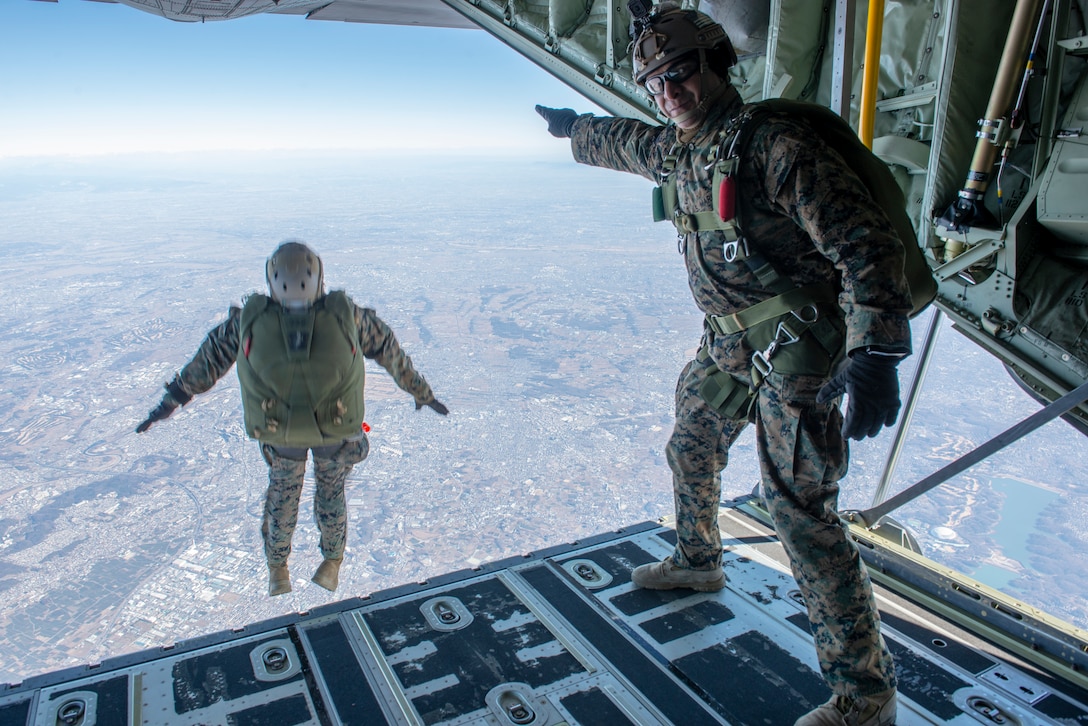 A U.S. Marine directs the Marines out of the aircraft during freefall parachute training during Yokota Parachute Operations at Yokota Air Base, Japan, Jan. 17, 2019. The Yokota Parachute Operation is designed to allow the Marines the opportunity to refine their skills with static line and free-fall parachuting. The Marine is a jump master with 3rd Reconnaissance Battalion, 3rd Marine Division.