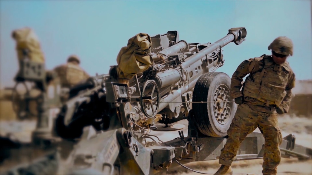 A soldier pulls a howitzer lanyard and fires a round.