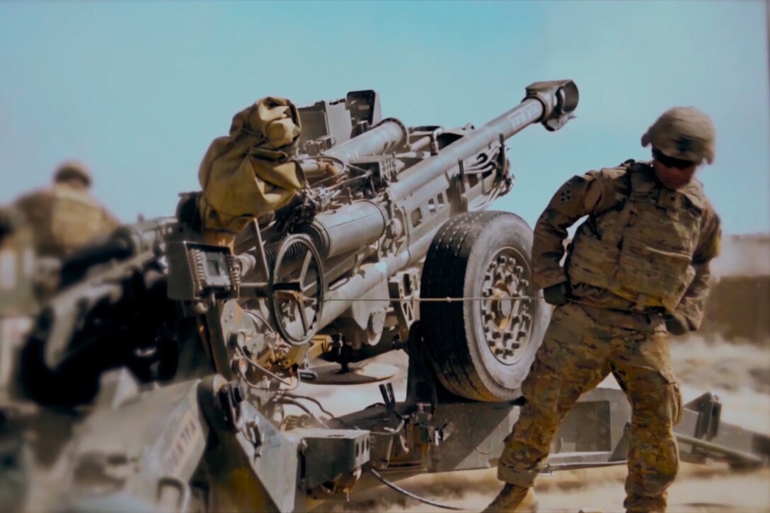 A soldier pulls a howitzer lanyard and fires a round.