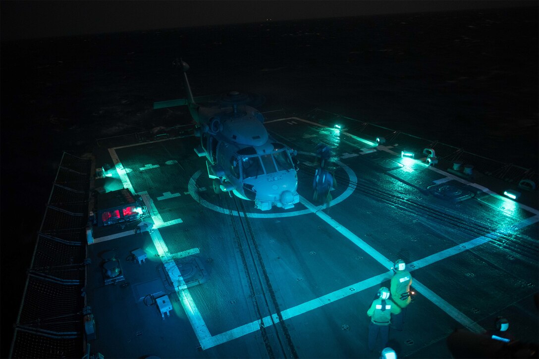 Sailors chock and chain an MH-60R Seahawk to a flight deck